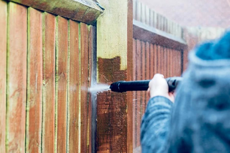 Technician soft washing a wooden fence in jacksonville fl